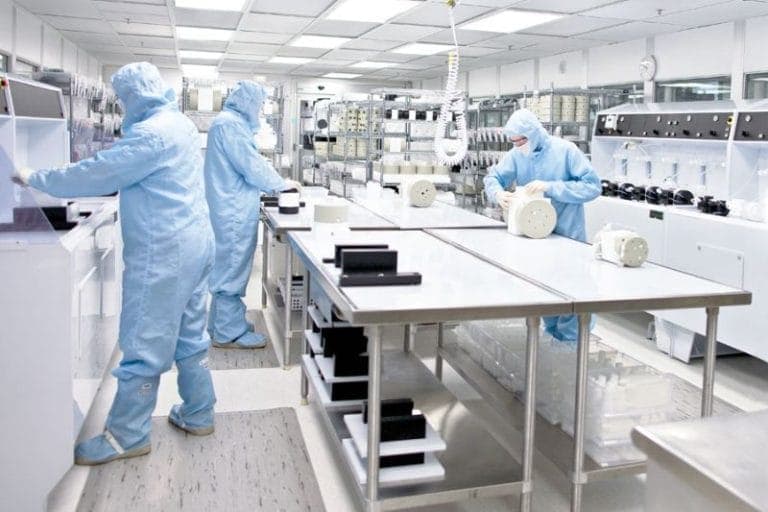 Modern clean room with advanced pressure control and air quality management, showing technician adjusting electronic panel and ceiling air filters.
